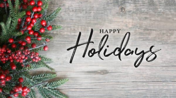 Happy Holidays Text with Holiday Evergreen Branches and Berries in Corner Over Rustic Wooden Background