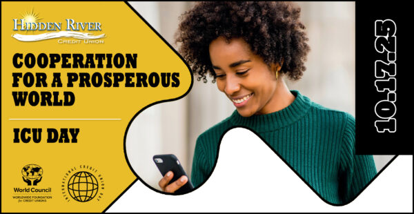 Woman in green sweater looking down at phone and smiling