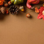 Autumn flat lay with pumpkins, pinecone, acorn, leaf, wheat on brown background. Seasonal harvest composition with copy space for fall, Thanksgiving or festive design