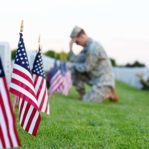 Soldier at a military cemetery kneeling by a grave.