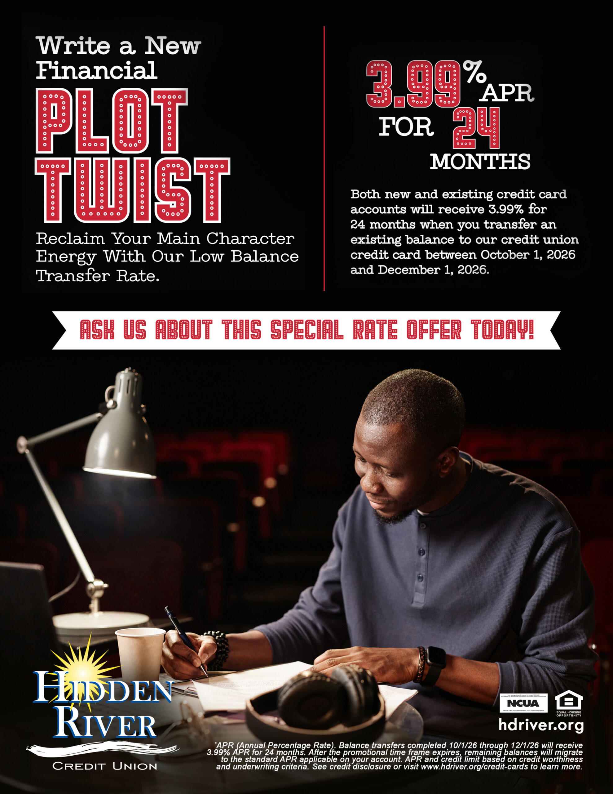 african american man sitting at desk in dark auditorium holding pen in hand with smile on his face while looking down at paper. Includes text "Write a New Financial - Plot Twist" with HRCU logo and 3.99% APR for 24 months."