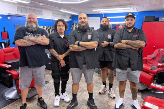 team of barbers standing in a line with arms folded