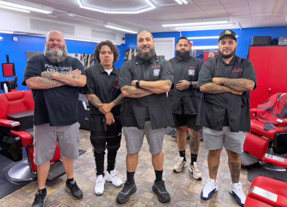 team of barbers standing in a line with arms folded