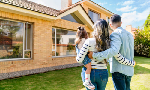 Loving family outdoors looking at their new house Rear view of a loving Latin American family outdoors looking at their new house - real estate concepts